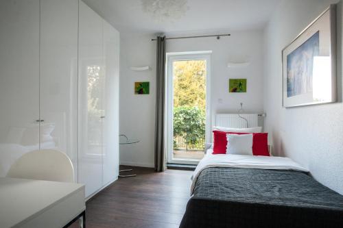 不莱梅Luxussuite mit Steinway-Flügel的一间卧室配有一张带红色枕头的床和一扇窗户