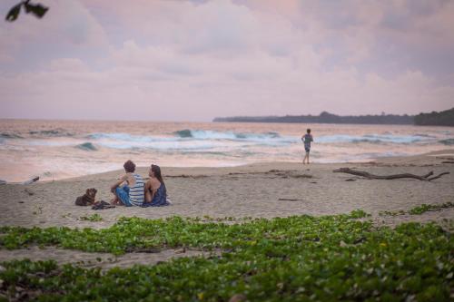 别霍港Playa 506 Beachfront Hostel的三人坐在海滩上