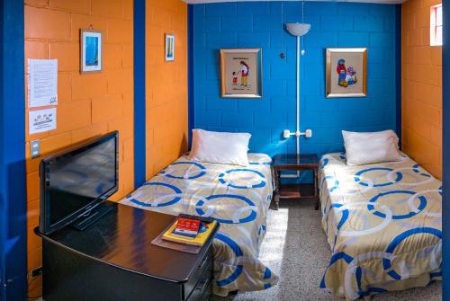 危地马拉Hostal Guatefriends的蓝色墙壁客房的两张床