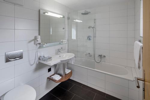 采尔马特凤凰酒店的浴室配有水槽、淋浴和浴缸。