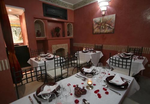 马拉喀什阿利利摩洛哥传统庭院的一间用餐室,配有白色的桌椅、盘子和玻璃杯