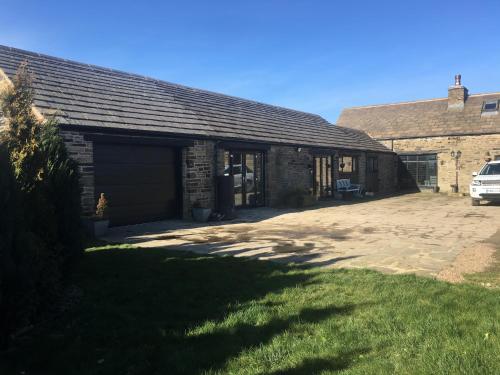 WortleyThe Coach House & The Stables Holiday Homes Windy Bank Hall Green Moor Yorkshire Peak District的一座带车库的建筑,旁边设有停车场