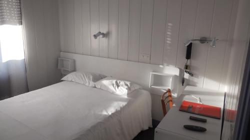 蓬德萨拉尔旅行者国际之家酒店的卧室配有白色的床和带电话的书桌。