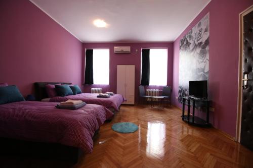 贝尔格莱德完美旅舍的紫色的客房配有两张床和一张沙发