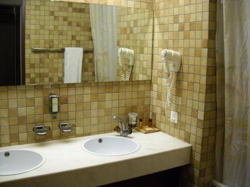 德莱蒙勒纳申尔酒店的一间带两个盥洗盆的浴室和墙上的一部电话