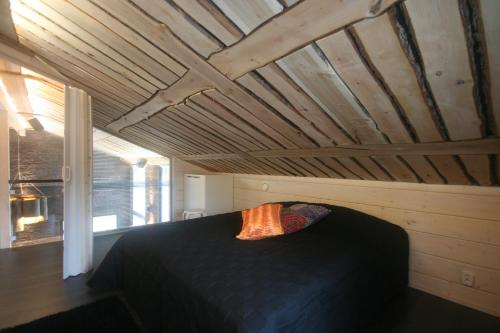 海尔迈Haarusmaa Holiday Apartment Härmä的一间卧室设有一张黑色的床和木制天花板。