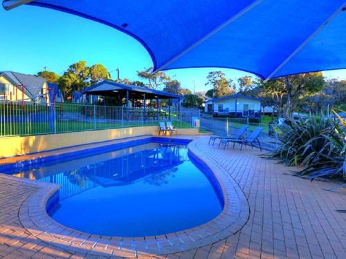 梅林布拉梅林布拉海滩小屋的一个带蓝伞和椅子的游泳池