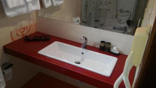 科扎尼尼菲力酒店的红色柜台上带白色水槽的浴室