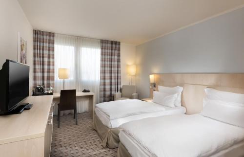 曼海姆曼海姆和平广场美居酒店的酒店客房设有两张床、一张桌子和一台电视。