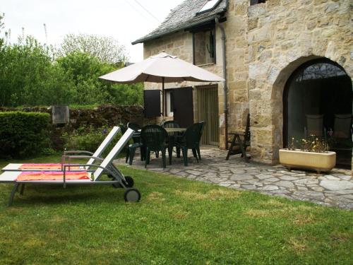 姆勒莎图Vintage holiday home near Rodez in Aveyron的庭院配有遮阳伞和桌椅。