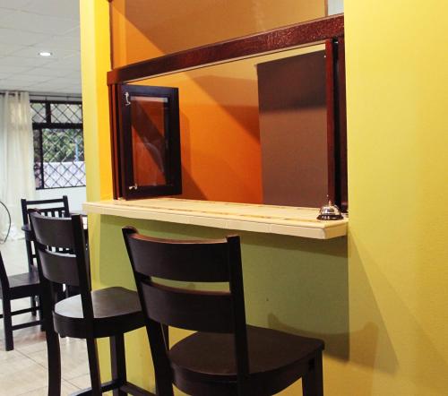圣萨尔瓦多Hostal de Asturias的酒吧配有四把椅子和镜子