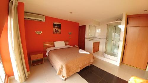 特鲁希略Libertad Hotel的一间卧室拥有橙色的墙壁、一张床和窗户