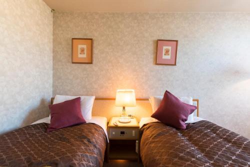 鱼津鱼津天空酒店的两张位于酒店客房的床铺,配有紫色枕头