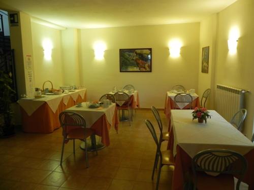 佛拉斯特拉伊尔萨拉瑟诺酒店的餐厅设有几张桌子和椅子,配有白色和橙色的桌子