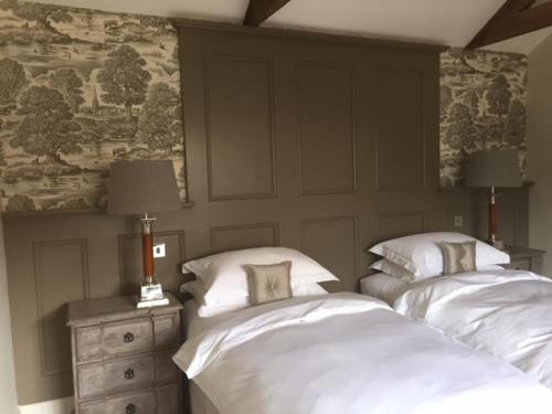 Little MassinghamHill Farm Bed and Breakfast的一间卧室设有两张床,墙上装饰有绘画作品
