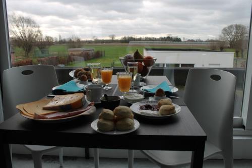 BerlaarB&B Het Museum的餐桌,带食物盘和橙汁杯