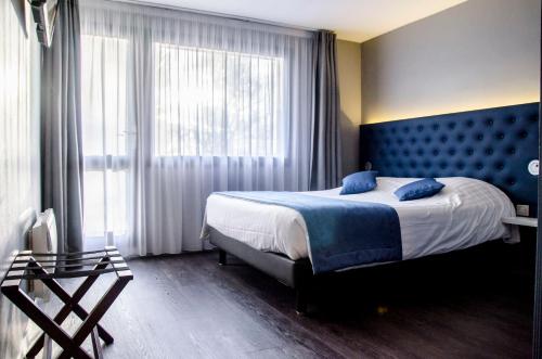 朗巴勒The Originals City, Hôtel Les Caps, Saint-Brieuc Est的一间卧室配有一张大床和蓝色床头板