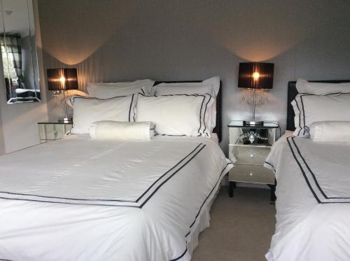 威克洛格伦呐喜茉莉住宿加早餐旅馆的一间卧室配有两张带白色床单和灯具的床。