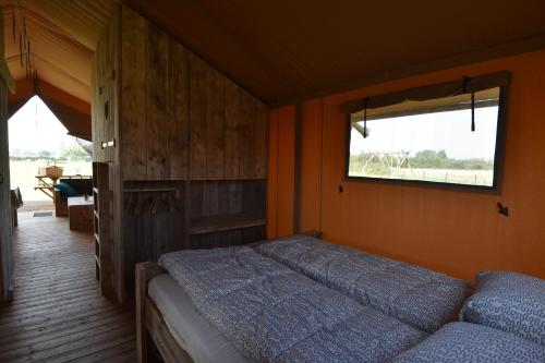 OostvleterenGlamping Aan de Vleterbeke的一间卧室设有一张床和一个窗口