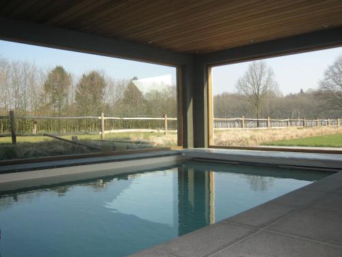 贝尔内姆Rural holiday home in former stables的享有围栏景致的别墅内的游泳池