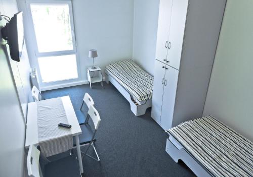 弗热希尼亚Hostel Września的一间设有两张床和一张桌子及椅子的房间