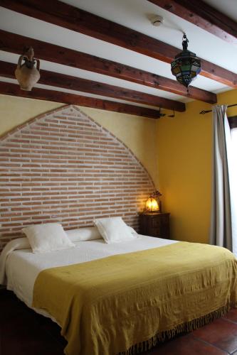 托莱多拉波萨达德马诺洛酒店的一间卧室设有一张带砖墙的大床