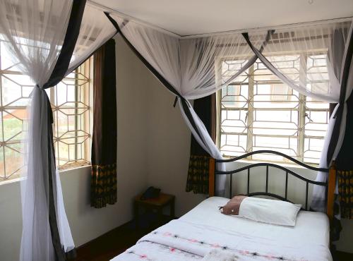 坎帕拉阿卡恰城市住宿加早餐旅馆的一间卧室设有天蓬床和2个窗户