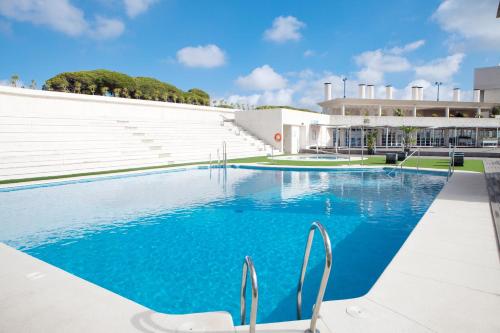 圣玛丽亚港波多雪利酒店的一座大楼前带椅子的游泳池