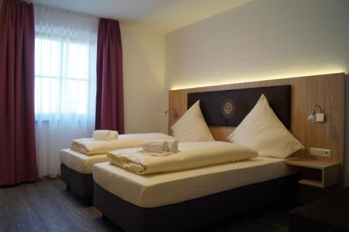 派森贝格Hotel Gasthaus Sonne的配有红色窗帘的酒店客房的两张床