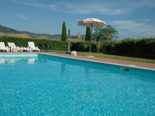 ContignanoSpacious Farmhouse in Pienza with Swimming Pool的一个带椅子和遮阳伞的游泳池
