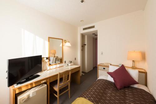 鱼津鱼津天空酒店的酒店客房配有一张桌子、一张床和一张书桌。