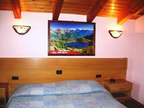 Gignod贝尔维尤酒店的卧室配有一张床,墙上配有电视。