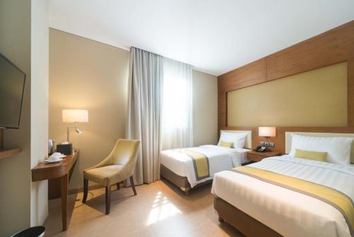 雅加达佩乔姆潘甘索蒂斯酒店的酒店客房,配有两张床和椅子