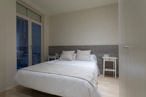 赫罗纳Bravissimo Cort Reial-2B的卧室配有一张带两张桌子的大型白色床