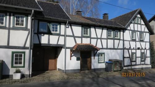 Schalkenbach麦森胡福度假屋的一座白色和黑色的古老建筑,设有门