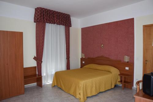圣乔瓦尼·罗通多Hotel Dei Cappuccini的一间卧室设有黄色的床和窗户。