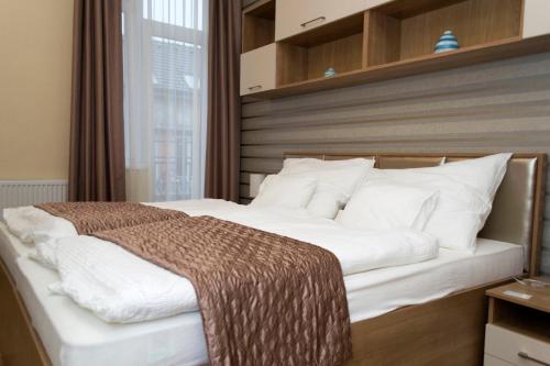 德布勒森Ditta Panzio的卧室配有一张带白色床单和枕头的大床。