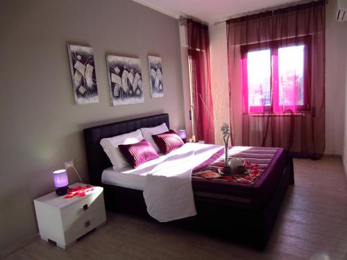菲乌米奇诺罗马机场就寝飞行酒店的一间卧室配有带粉红色枕头的床和窗户。
