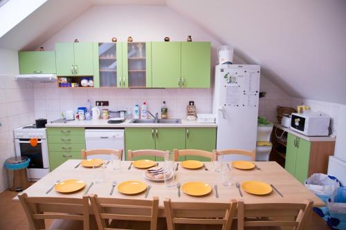 VlasenicePenzion U Rudolfů的厨房配有绿色橱柜和一张带椅子的木桌