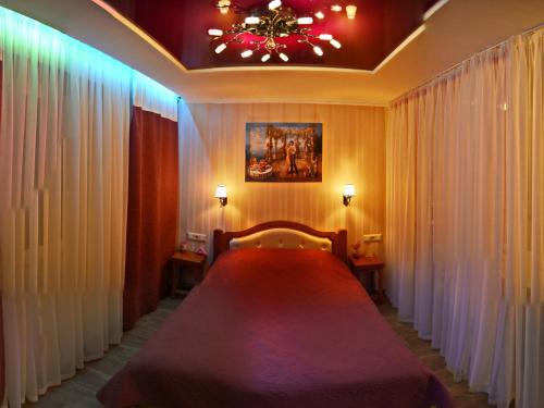 切尔尼戈夫ApartLux Chernigov的一间卧室配有一张大床、窗帘和吊灯。