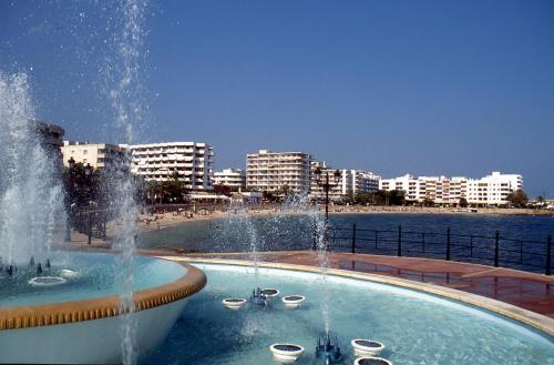 圣埃乌拉利亚Hostal y Apartamentos Santa Eulalia的游泳池旁的喷泉,海滩上建有建筑