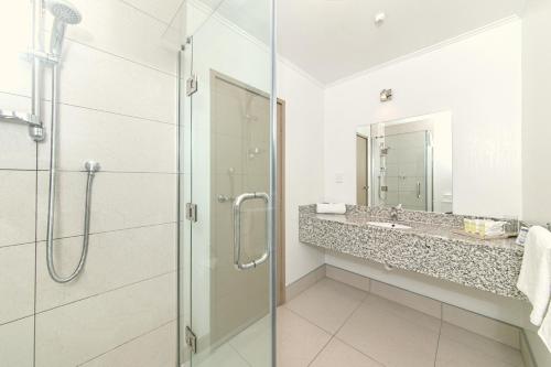 奥克兰机场入口酒店的一间带玻璃淋浴和水槽的浴室