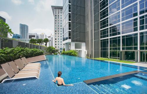 新加坡Ascott Orchard Singapore的坐在城市游泳池里的男人
