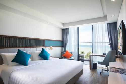芽庄芽庄西塔迪纳海滨酒店的酒店客房配有带蓝色和橙色枕头的床。