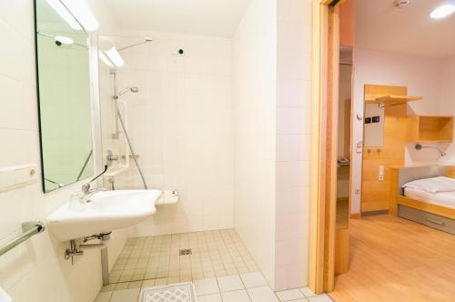 博尔扎诺博尔扎诺科尔平豪斯酒店的一间带水槽的白色浴室和一间卧室