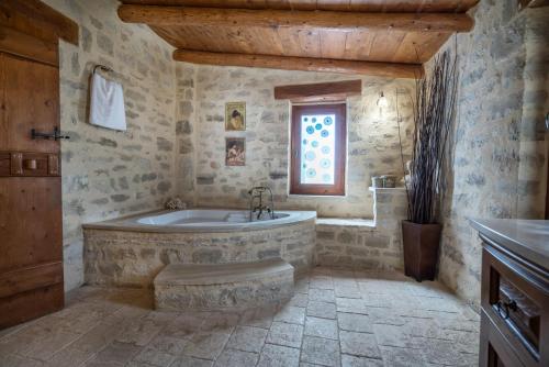 普林斯Villa Kalliopi的带浴缸和窗户的石质浴室