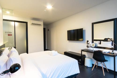 清迈清迈门贝德酒店 - 仅限成人的一间卧室配有一张床、一张书桌和一面镜子