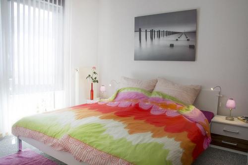 奥斯特巴特宁哈根Ferienwohnung Sandpiper的一间卧室配有一张带彩色毯子的床