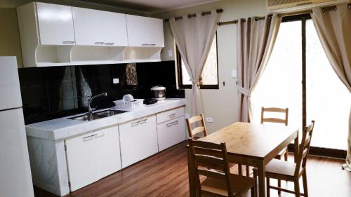 查兰卡诺亚塞班家庭公寓的厨房配有白色橱柜和桌椅