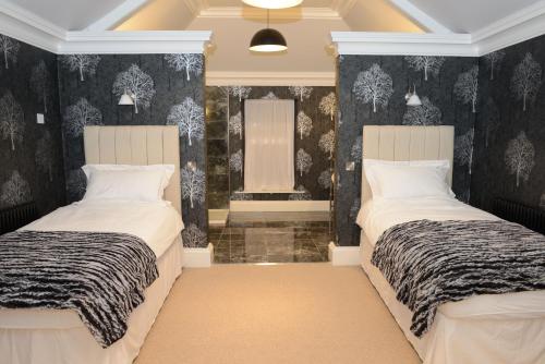 洛克比Bishopcleugh Guest House的配有黑白壁纸的客房内的两张床